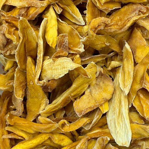 Dried yellow mango pieces in a clear container with a wooden background